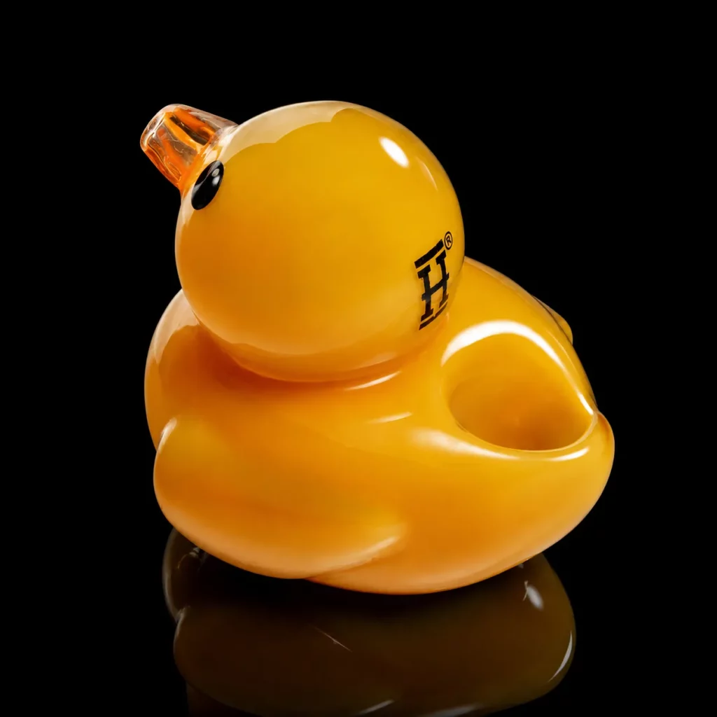 Pipe Duck HEMPER vue de dos montrant le foyer creusé dans le dos du canard en verre jaune et le logo H sur la tête
