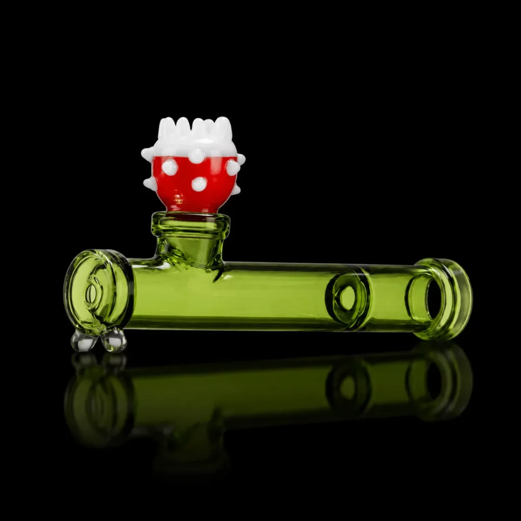 Pipe Piranha HEMPER en verre borosilicate vert en forme de tuyau rétro-gaming avec tête de plante carnivore rouge à pois blancs en foyer