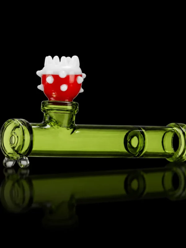 Pipe Piranha HEMPER en verre borosilicate vert en forme de tuyau rétro-gaming avec tête de plante carnivore rouge à pois blancs en foyer