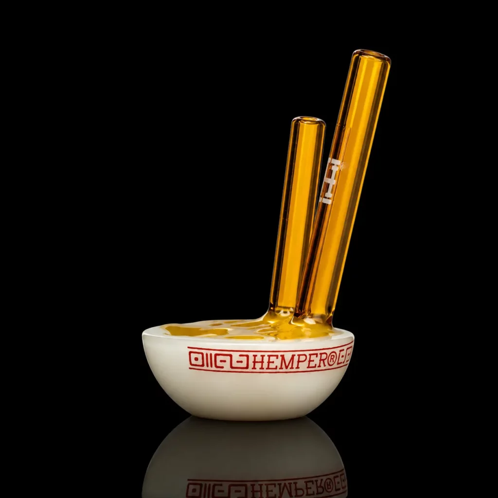 Pipe Ramen HEMPER en verre en forme de mini bol de ramen blanc à frise rouge avec nouilles dorées texturées et baguettes ambrées dont une sert d'embout